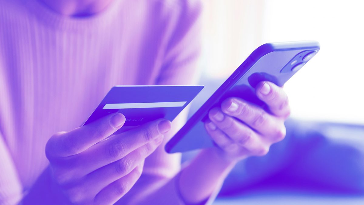 Pessoa segurando um cartão e um celular nas mãos
